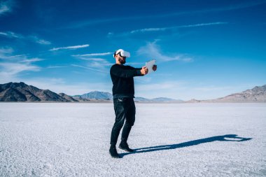 ABD 'de zaman geçirirken dağlık arazinin yakınlarında tabletle oyun oynayan, VR kulaklıklı, tanınmayan bir adamın tüm vücudu.