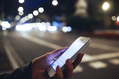 Akşam vakti şehir caddesinde vakit geçirirken cep telefonundan anonim kadın mesajlaşmasının yan görüntüsü