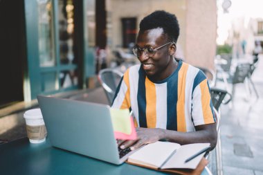 Koyu tenli erkek kullanıcı, dizüstü bilgisayar teknolojisiyle blog yayını oluşturmak için uygulama yüklüyor, 