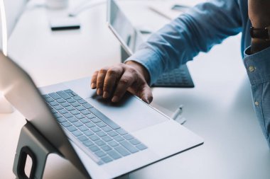 Modern ofisteki bilgisayarın üstünde çalışırken resmi kıyafetler içinde dokunmatik ped kullanan isimsiz bir erkek yöneticinin yüksek açılı görüntüsü.