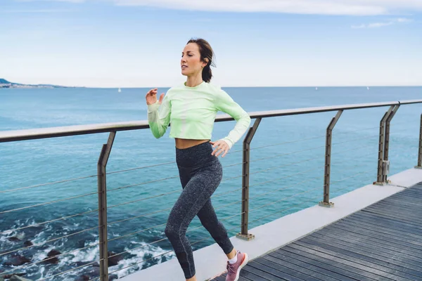 40歳アクティブな健康的な女性アスリートスポーツウェアジョギングと雲のない青空に対して木製の桟橋上で温暖化 — ストック写真