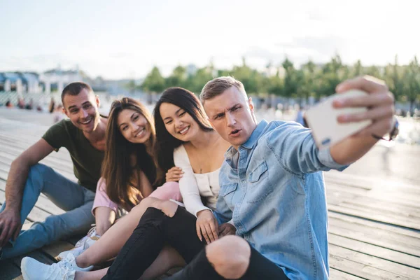 Grupo Amigos Multirraciais Animados Sorrindo Enquanto Sentados Juntos Tirando Selfie — Fotografia de Stock