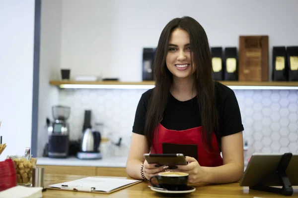 明るい繁栄ブルネット女性Barista楽しみます仕事でコーヒーショップ作る注文上のアプリ経由でデジタルタブレット — ストック写真