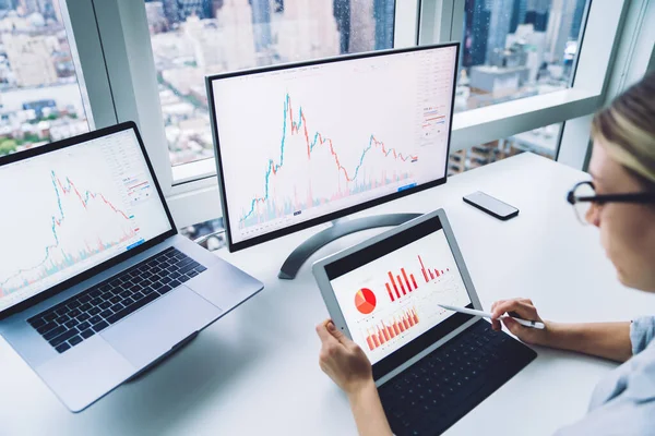 Modern çalışma alanındaki masaüstü bilgisayarlarının yanında grafikler bulunan tablet ekranda stilus ile gösterilen ekin kadın simsarının yukarıdan görünüşü