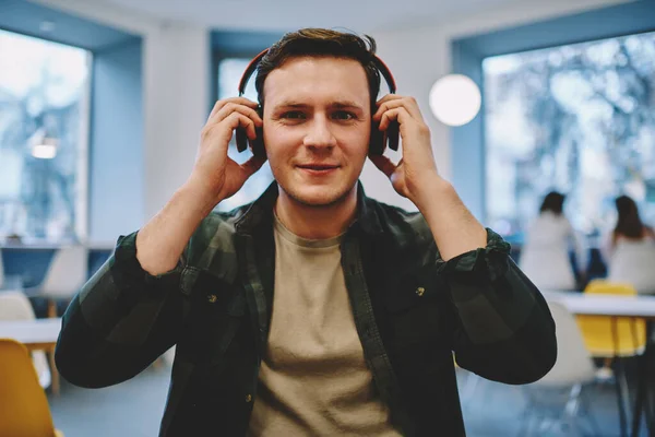 Glad Young Man Casual Clothes Looking Camera Touching Headphones Listening — Stock Photo, Image