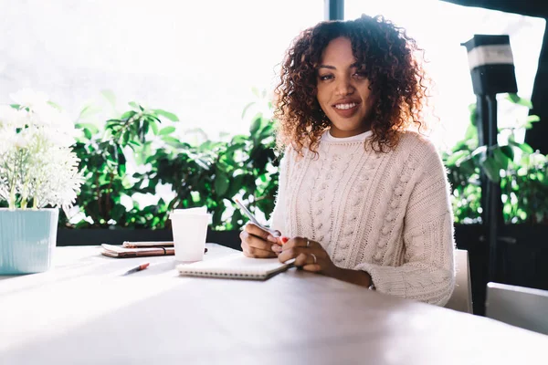 Vrolijke Afro Amerikaanse Krullende Vrouw Zit Aan Tafel Met Werkboek — Stockfoto