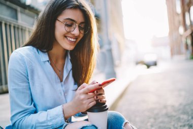  Gözlüklü komik bayan turist web sitesinde ağ kurmak için cep telefonu aygıtına medya uygulaması yüklüyor