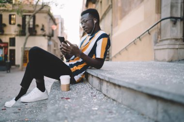 Şehirde boş zamanlarında online rezervasyon ve bankacılık yapmak için akıllı telefon kullanan bin yıllık hippi adamın yan görüntüsü