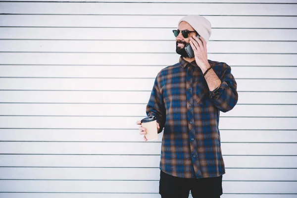 Smiling hipster guy using roaming connection for calling at promotional background with copy space area