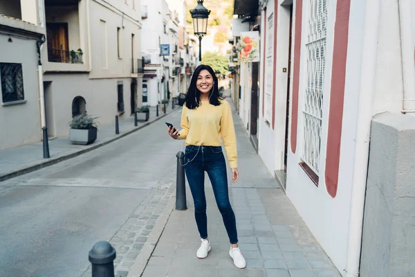 Glimlachende Etnische Vrouw Casual Outfit Oortelefoons Lopen Stoep Van Smalle — Stockfoto