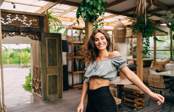 夏の日にカフェに立ってカメラを見ながら笑顔でカジュアルな服を着た楽観的な民族女性 — ストック写真