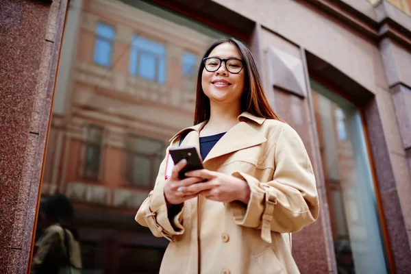 笑顔の優しいアジアの女性がカメラを見ていると 路上に立っているスマートフォンにメッセージを送りながら休憩 — ストック写真