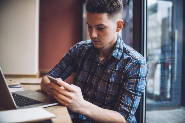 Konzentrierter Männlicher Unternehmer Lässiger Kleidung Sitzt Tisch Und Blättert Smartphone — Stockfoto