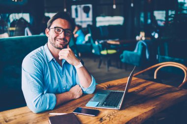 Ve kameraya gülümseyen optik gözlük. Netbook 'ta çalışırken. Reklam alanına yakın otururken.