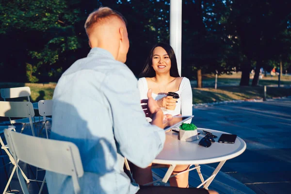 穿着休闲装的快乐夫妻坐在户外咖啡馆的桌旁 一边聊天 一边喝着外卖咖啡 一边浏览平板电脑 — 图库照片