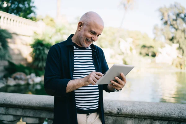 Gülümseyen son sınıf öğrencisi modern cihazlarda internetten ağ yayınlarını okuyor ve online rezervasyon yapıyor.