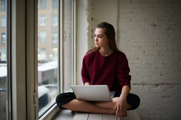 Serious Female Remote Worker Casual Clothes Looking Away Sitting Windowsill —  Fotos de Stock