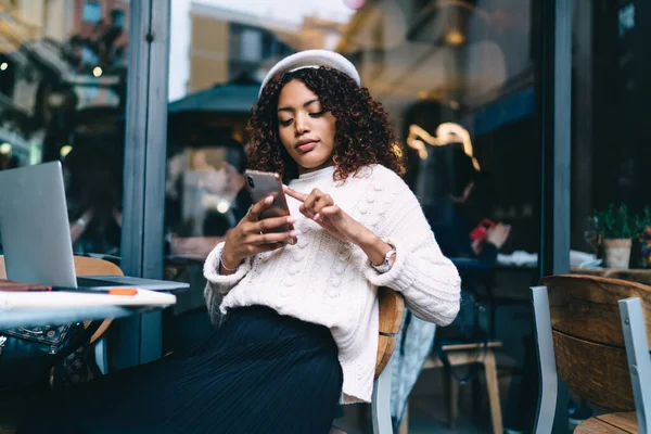 Koyu tenli yetenekli kadın. Kafe terasında çalışıyor. Cep telefonu 4G 'ye bağlı.