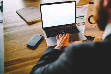 Ofisteki ahşap masada oturan ve elinde dizüstü bilgisayarla çalışan tanınmayan işadamının el ele verdiği grafikten.