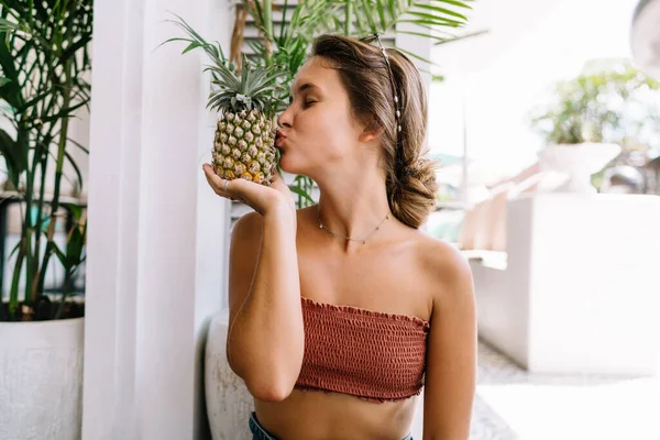 パイナップルを持ち 夏休みを熱帯リゾートで過ごす楽しい夏服の幸せな若い茶色の髪の女性 — ストック写真