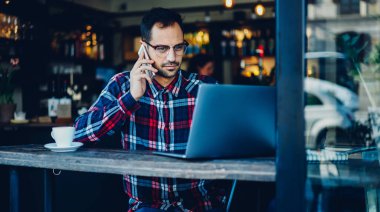 İnternet sitelerinde gezinen web bilgilerini tartışmak için çağdaş akıllı telefon aygıtı üzerinden meslektaşıyla iletişim kuran beyaz bir adam