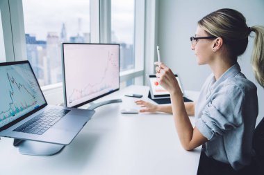 Masaüstü bilgisayar monitöründeki verileri analiz eden genç tüccarın yan görünümü.