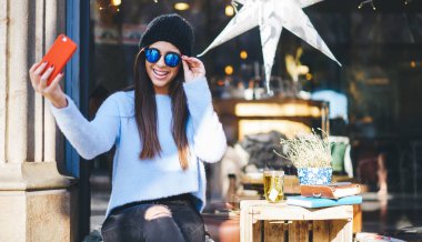 Mobil uygulama üzerinden pozitif selfie görüntülerine tıklamak için ön kameraya gülümseyen mutlu beyaz blog yazarı