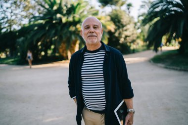 Şehirde boş zamanlarında kameraya bakan modern dokunmatik aletli yaşlı bir gezginin yarım boy portresi.