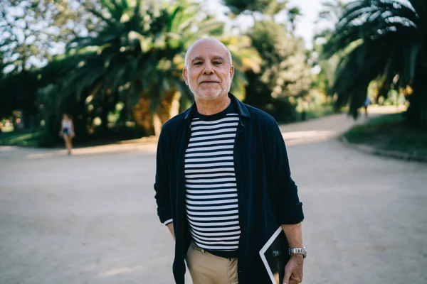 Şehirde boş zamanlarında kameraya bakan modern dokunmatik aletli yaşlı bir gezginin yarım boy portresi.