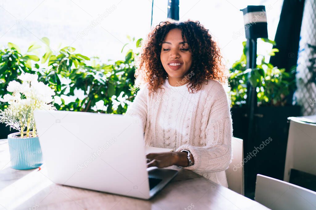 Cheerful african american woman having distance job on cafe terrace share content and publications