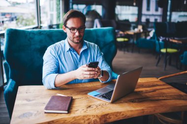Gözlüklü başarılı bir erkek girişimci, kafede çalışan akıllı telefon ile ilgili mesaj ve multimedya dosyaları gönderiyor. Deneyimli pazarlama yöneticisi, proje için dizüstü bilgisayar paylaşımı fotoğraflarıyla telefon verilerini senkronize ediyor.