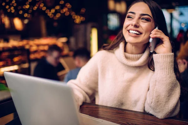 Optymistyczna Młoda Kobieta Freelancer Swobodnym Swetrze Mówi Przez Telefon Komórkowy — Zdjęcie stockowe