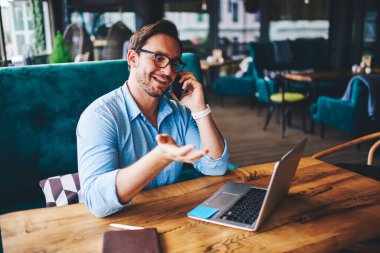 Gözlüklü müreffeh işadamı, iş arkadaşı ile mobilede konuşma hakkında fikir alışverişinde bulunuyor. Genç erkek serbest çalışan, dizüstü bilgisayardaki yazılımı güncellerken müşteri destek servisiyle irtibata geçiyor.