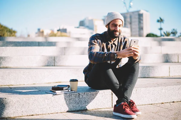 Young hipster guy enjoying smartphone mobility networking during leisure in city using 4g wireless for connection