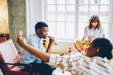 Düşünceli, düşünceli, Afrikalı Amerikalı bir erkeğin dairede arkadaşlarıyla masa oyunu oynarken biberondan içmesi.