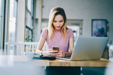 Milenyum yeniyetme kız kafeteryadaki internet bağlantısını kullanarak modern akıllı telefon teknolojisi üzerine video yayınını izliyor.