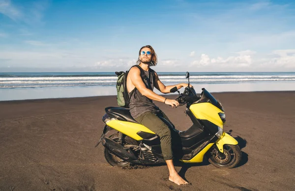 夏休みに砂浜に駐輪するバイクで再現されたカジュアルな服やサングラスの若い素足の男性ヒップスターのコンテンツのサイドビュー — ストック写真