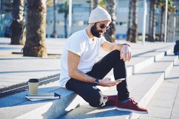 Sakallı erkek blogcu cep telefonu uygulaması üzerinden web rezervasyonları yapmak için 4G internete bağlanıyor