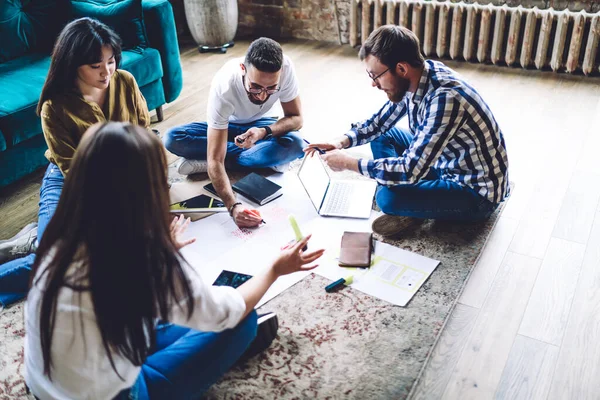 Genç bir grup profesyonel grafik tasarımcısı, beyin fırtınası sırasında plan çizimini tartışmak için konuşuyor.