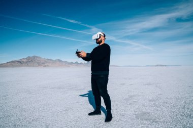 ABD 'de kurumuş gölün üzerinde duran siyah kazaklı, tanınmayan bir adamın yan görünüşü doğada sanal gerçekliği deneyimlerken