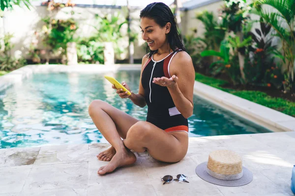 Side View Young Ethnic Female Swimwear Using Smartphone While Sitting — стоковое фото