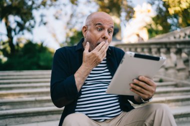 Modern dokunmatik ekrandaki uygulamayı kullanarak ilginç bir ağ videosu izleyen şaşırtıcı erkek seyahat blogcusu