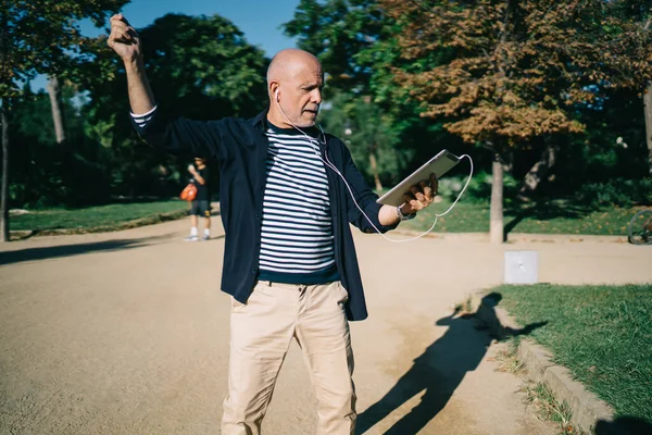 Elektronik kulaklıklar takmış Kafkasyalı son sınıf öğrencisi şehirde rock müzik dinliyor ve yüreği genç hissediyor.