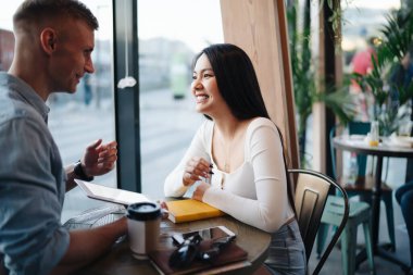  Mutlu hipsterlar birlikte kahve dükkanında vakit geçirip teknolojinin blog yazmak için kullanılması hakkında konuşuyorlar.