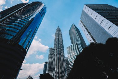 Malezya 'nın Kuala Lumpur kentindeki yüksek ve modern binaların alçak açısı güneşli bir günde bulutlu mavi gökyüzünde.