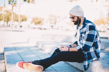 Orta Doğulu erkek blogcu, elektronik kulaklıklar kullanarak modern akıllı telefon cihazına medya uygulaması yüklemek için 4G internete bağlanıyor