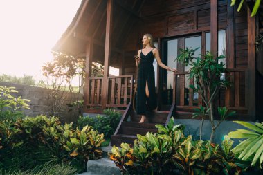 Sıcak yaz havasının tadını çıkarırken, egzotik bitkilerin arasında akıllı telefonlu çıplak ayaklı bir kadın.