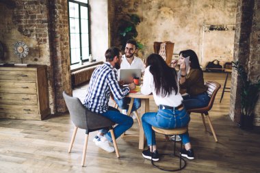 Çatı katında işbirliği yapan mutlu çok ırklı öğrenciler öğrenim için dostça buluşmanın keyfini çıkarıyorlar.