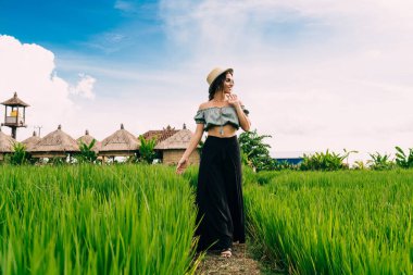 İspanyol bayan turist, Bali 'de yaz tatilinin tadını çıkarırken egzotik köyün yakınlarındaki yemyeşil çayırlarda yürüyüş yapıyor.