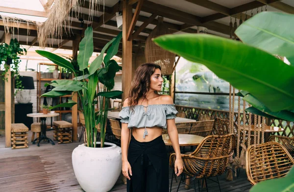 Pensive Ethnic Female Trendy Outfit Standing Cafe Green Plants Wooden — Stockfoto